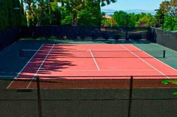 a tennis court with a red surface and a black fence