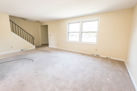 the living room and dining room of a new home with carpet and a window