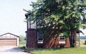 an old brick house with a tree in front of it