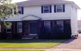 A white house with a black front door and steps.
