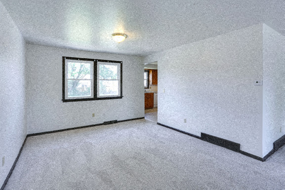 an empty living room with a window and white walls