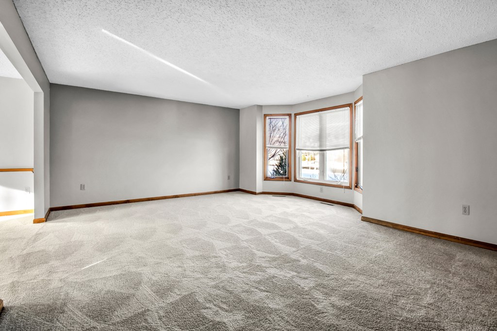 an empty living room with a large window and a carpeted floor