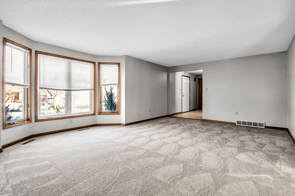 an empty living room with large windows and a carpeted floor