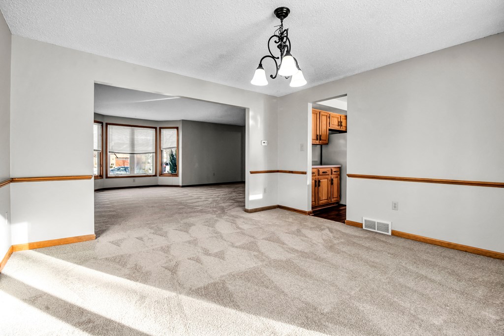 the living room and dining room of an empty house with a carpeted floor