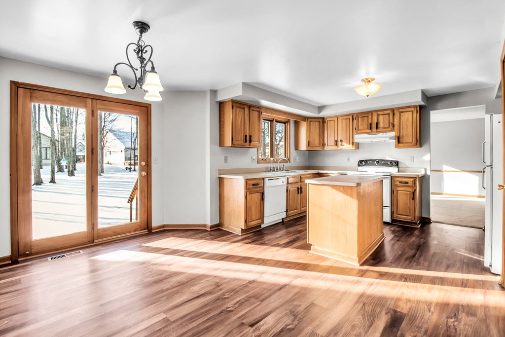 an empty kitchen with wooden cabinets and a door to a patio