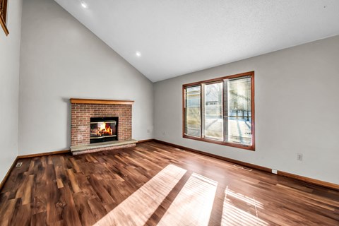 the living room of a house with a fireplace and wooden floors