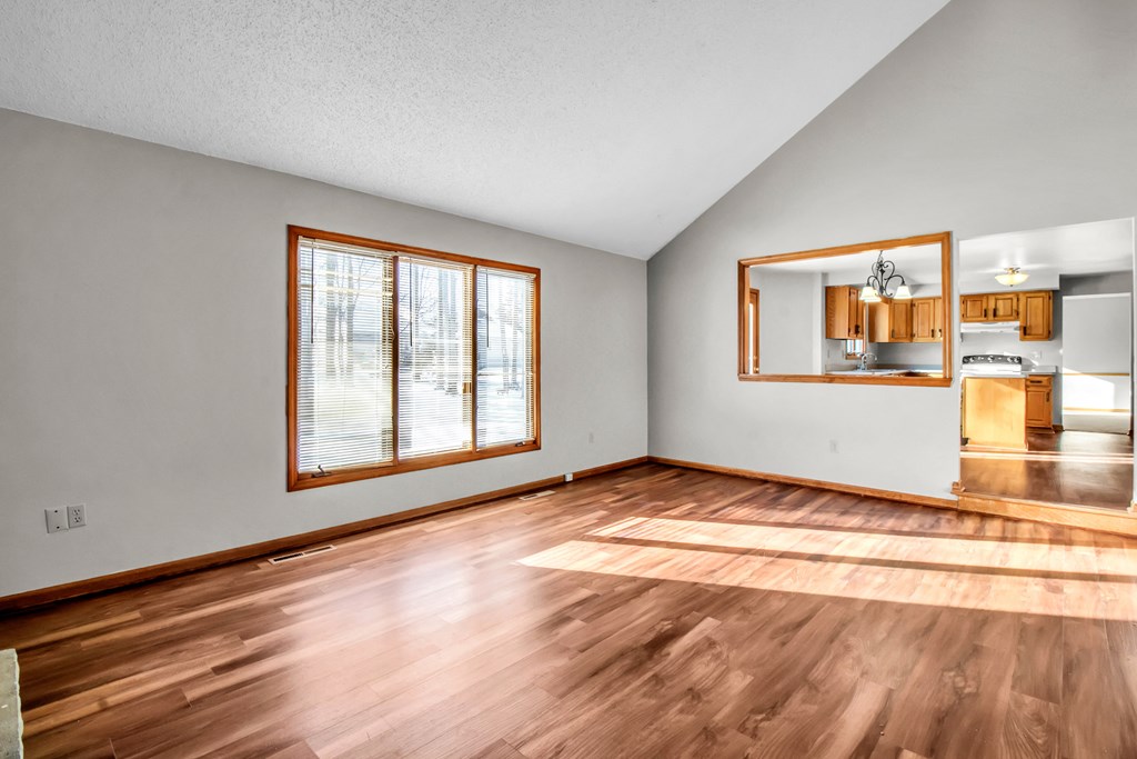 the living room of a rental house with wood flooring and a window