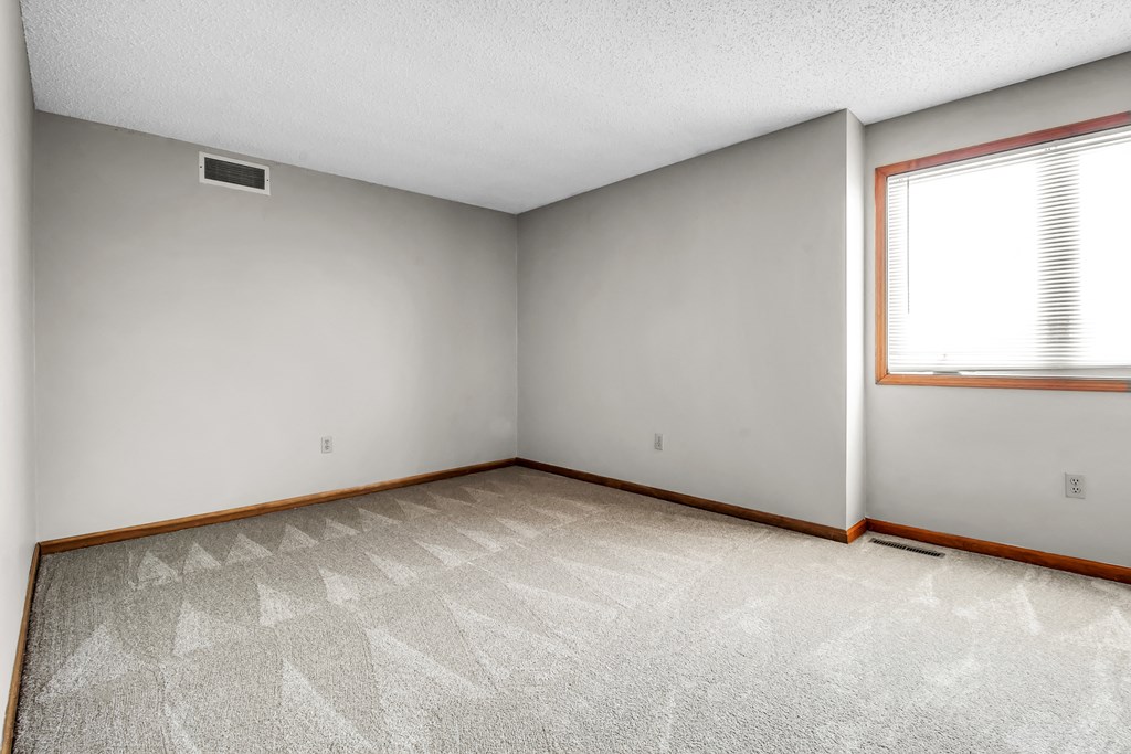 the living room of an empty house with white walls and a window