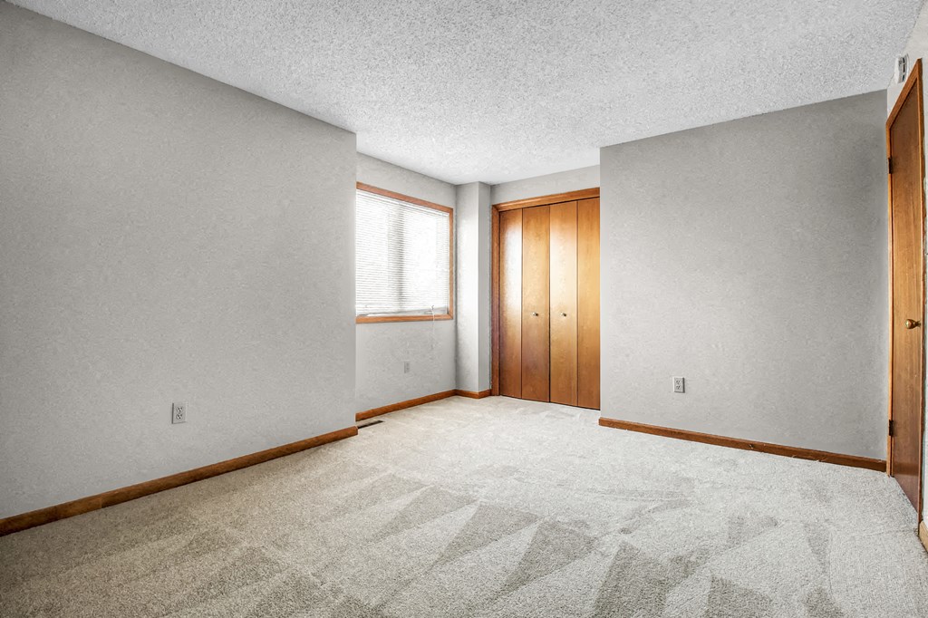 an empty room with a carpeted floor and a closet