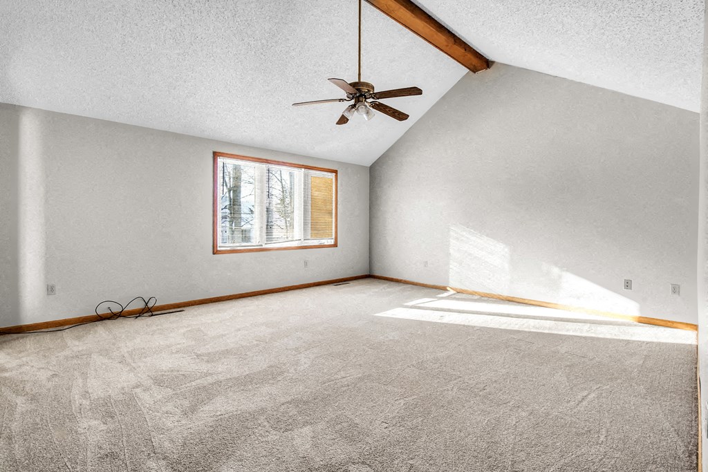 an empty living room with a ceiling fan and a window