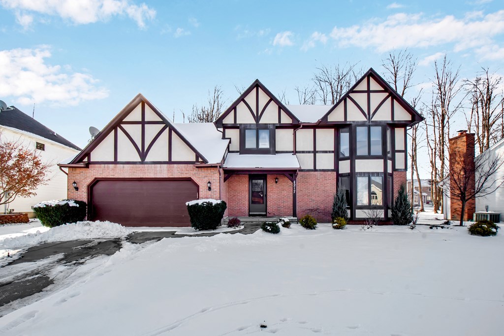 a red brick house with a garage in the snow