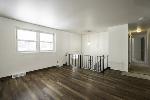 the living room and entryway of a house with hardwood floors and white walls