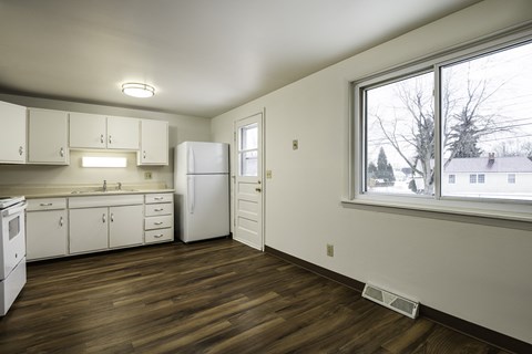 a kitchen with a large window and white cabinets and appliances