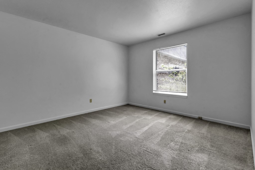 the living room of a house with white walls and a window