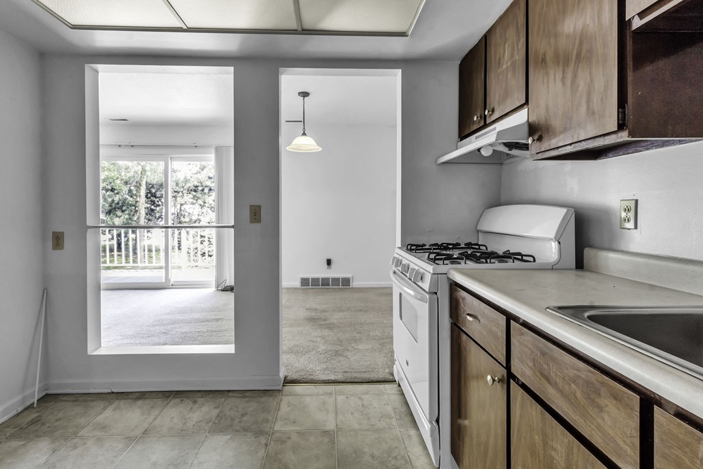 an empty kitchen with white appliances and wooden cabinets