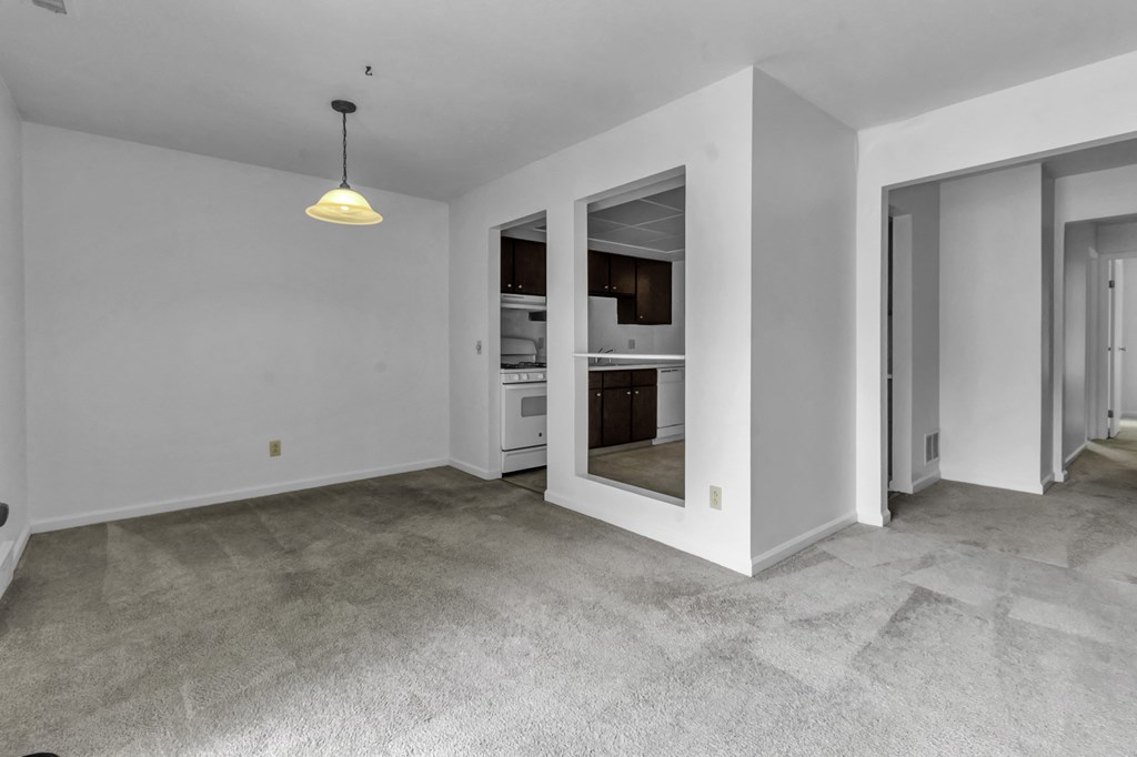 a living room with white walls and a door to a kitchen