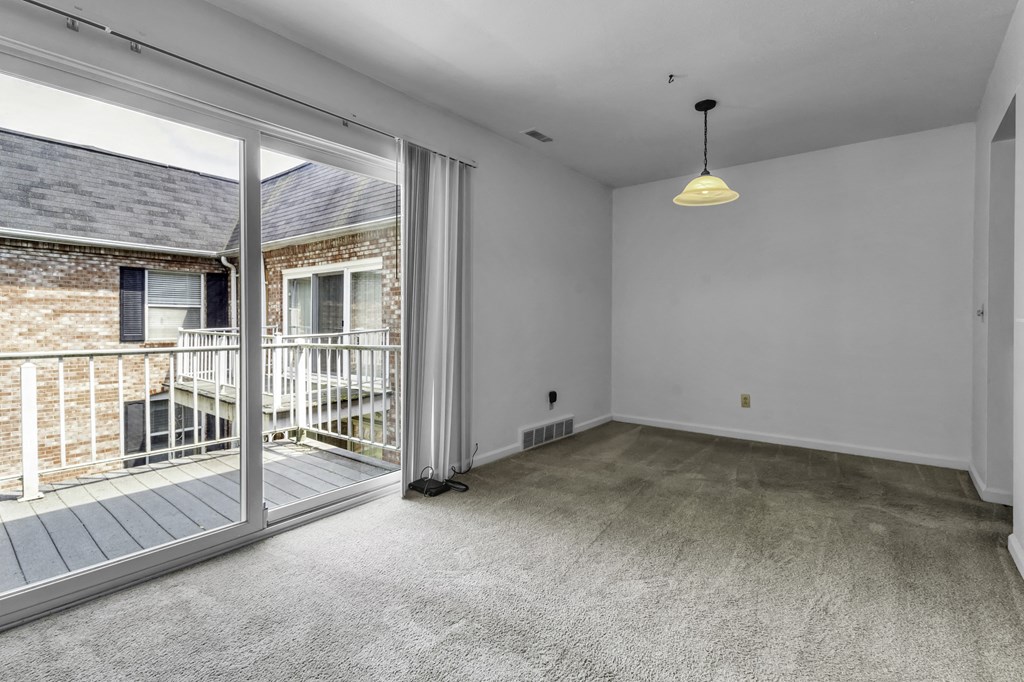 an empty living room with a sliding glass door to a balcony
