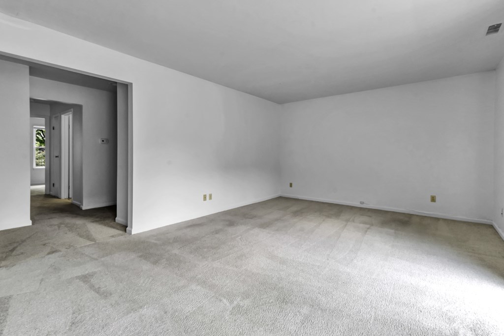 the living room of an empty house with white walls and concrete floors