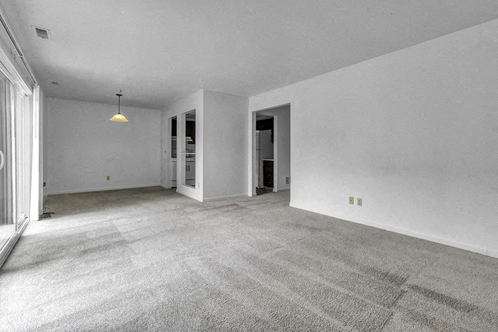 an empty living room with white walls and carpet