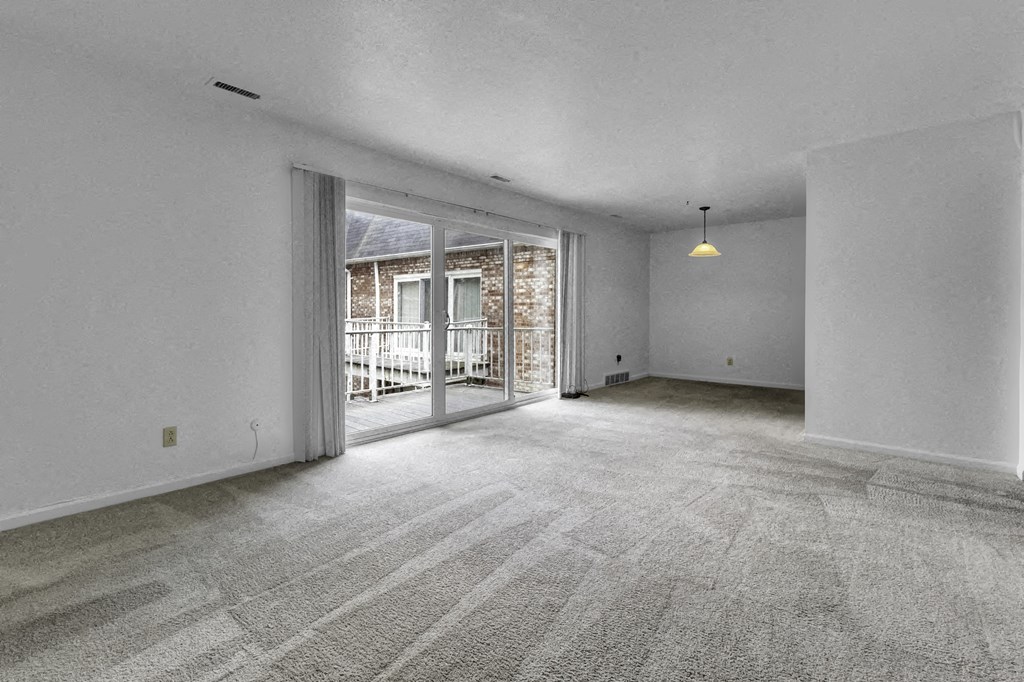 an empty living room with a sliding glass door to a balcony