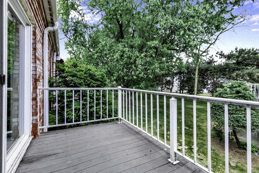 a balcony with a view of a yard and trees