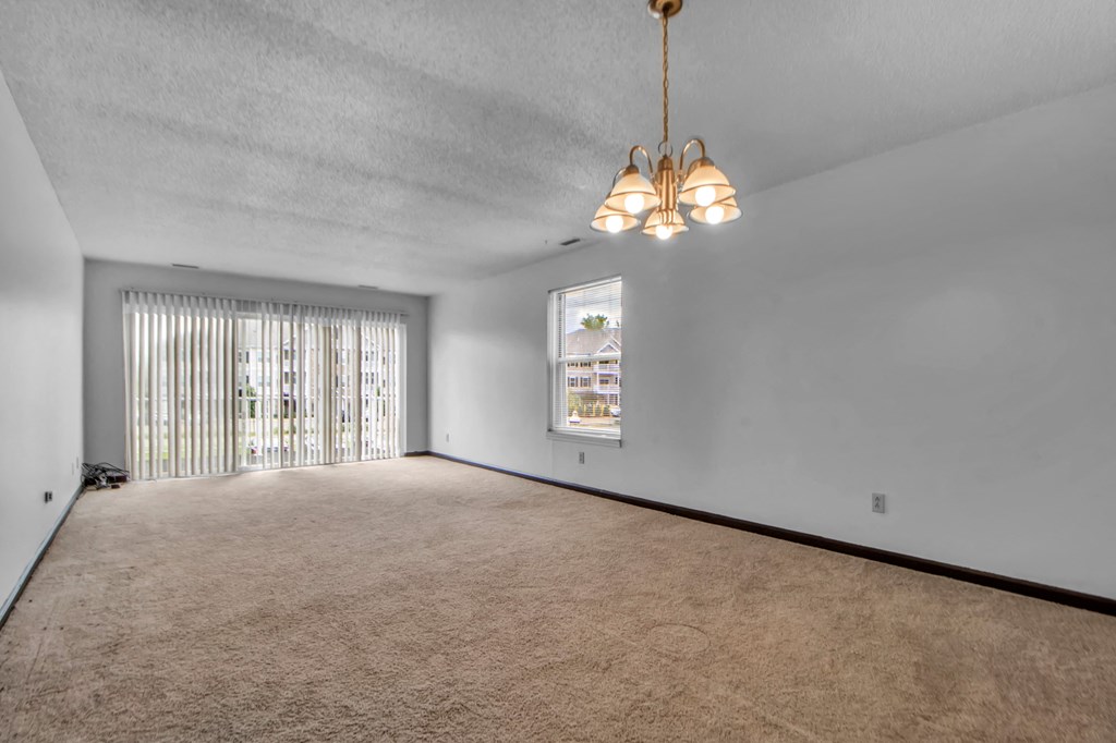 A room with a carpeted floor and a window with blinds.