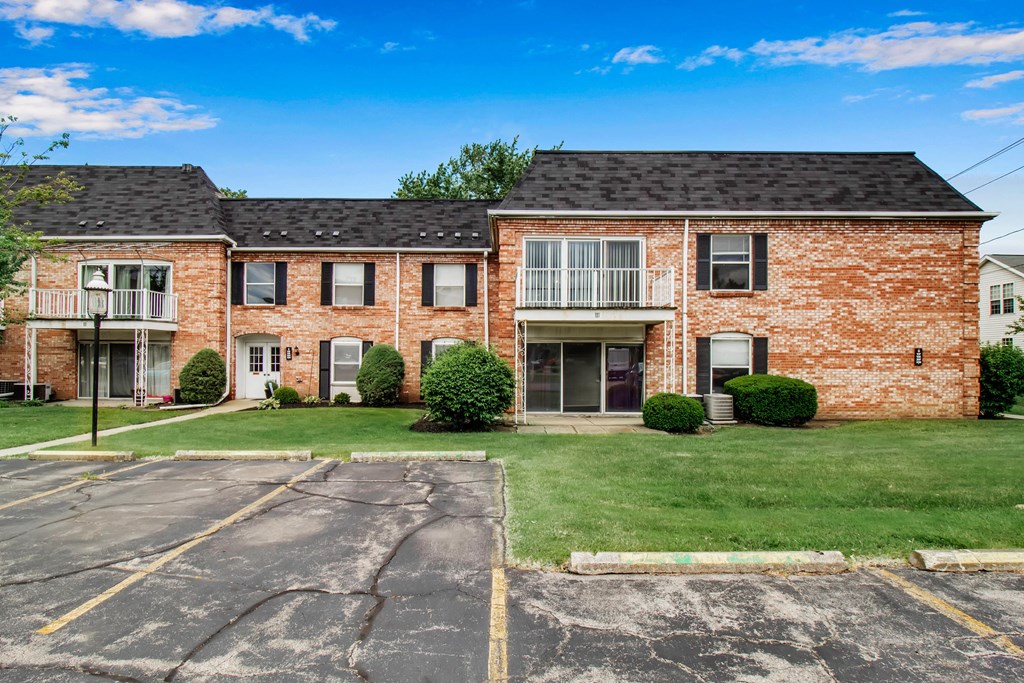 A brick building with a parking lot in front.