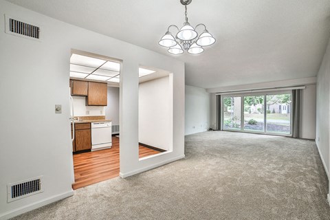 an empty living room and kitchen with a sliding glass door