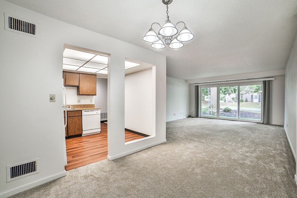 an empty living room and kitchen with a sliding glass door
