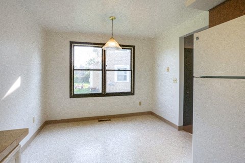 an empty living room with a window and a refrigerator