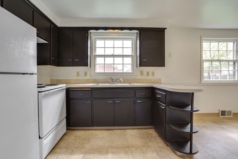 A kitchen with black cabinets and a white refrigerator.
