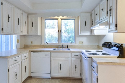 a kitchen with white cabinets and a stove and a window