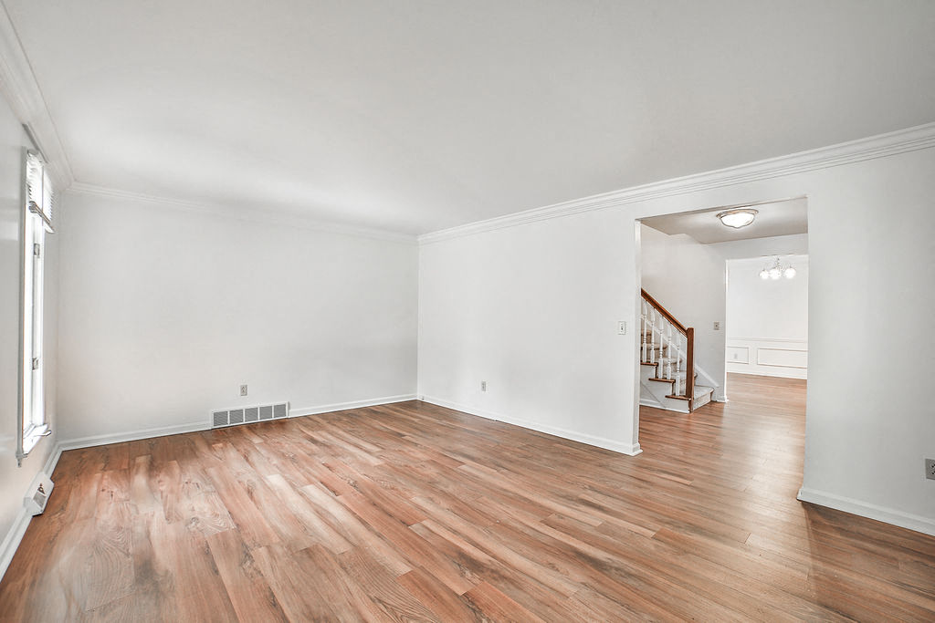 the living room and dining room with hardwood floors and white walls