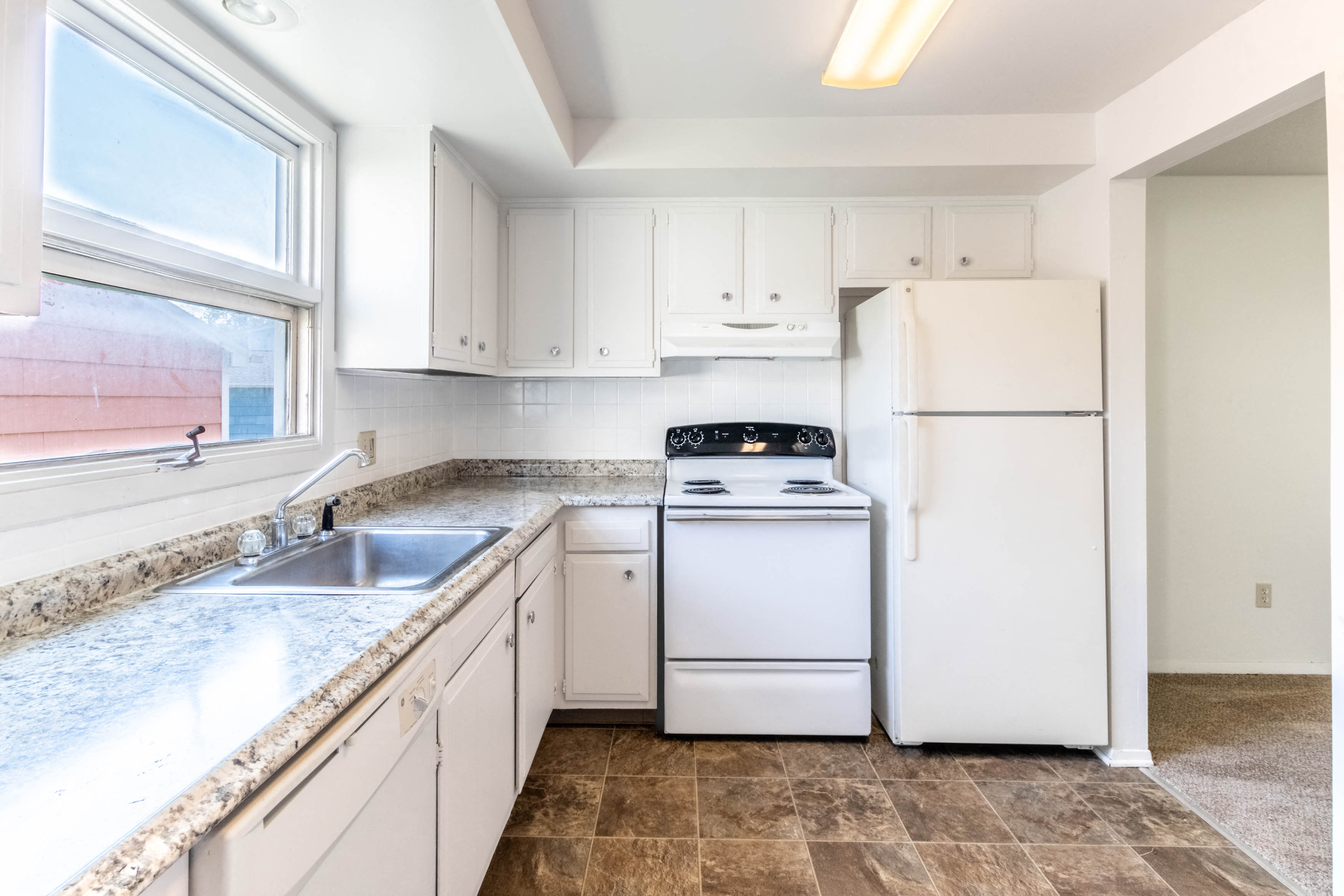 A kitchen with white appliances and cabinets.