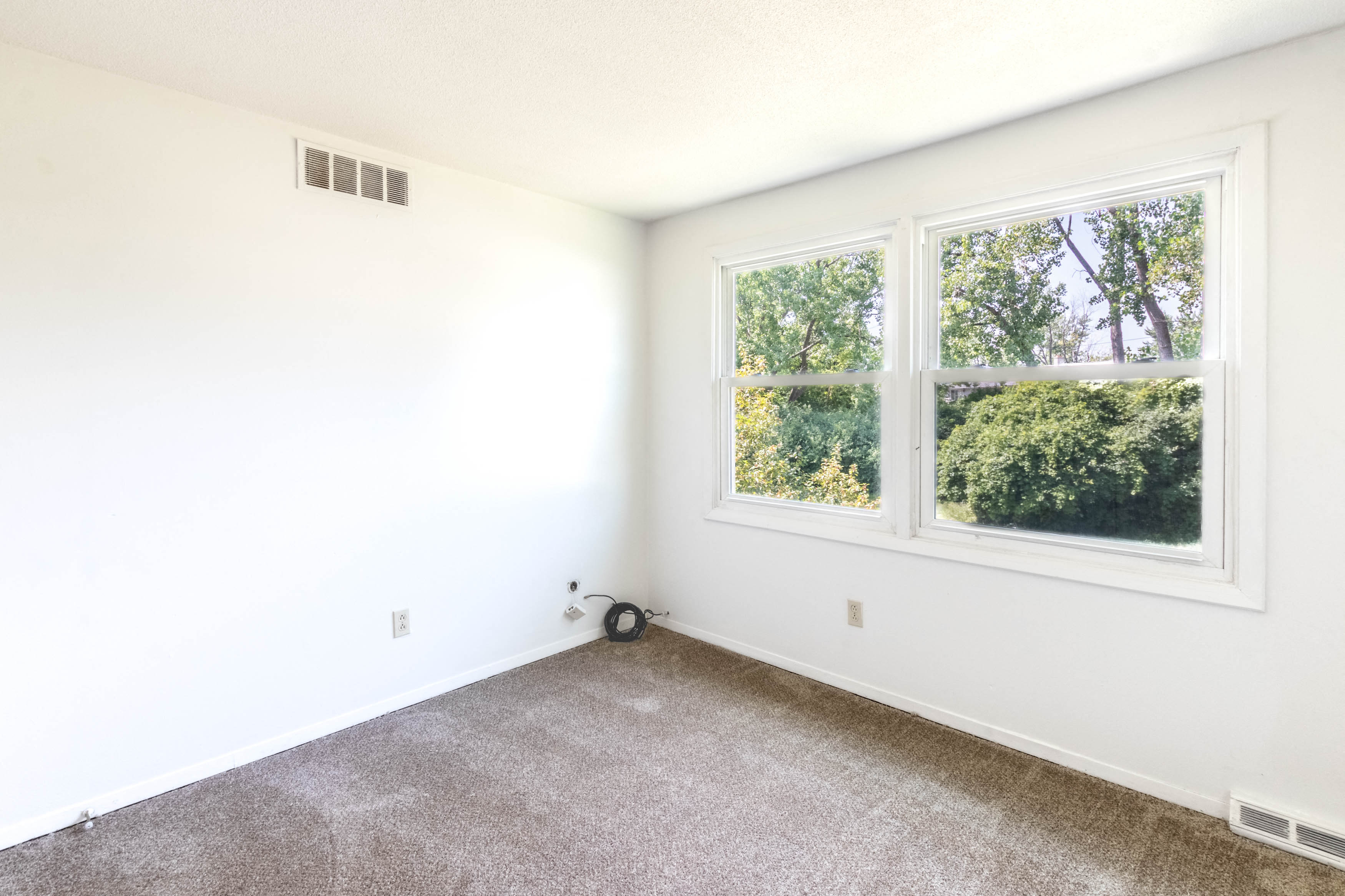 A room with a window showing trees outside.