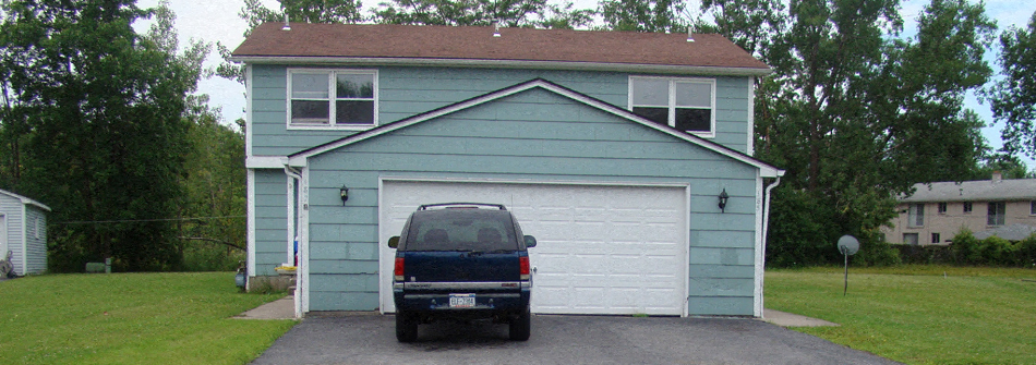 A blue house with a garage door and a car parked in front.