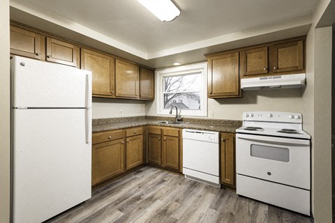 A kitchen with white appliances and wooden cabinets.
