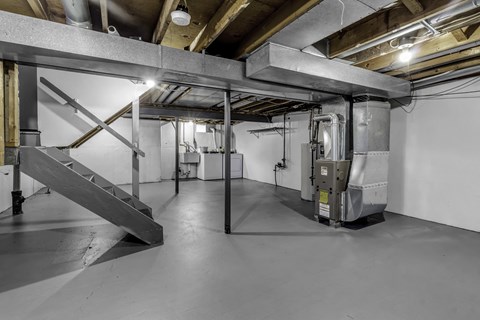 A large, empty industrial space with a staircase and ductwork.