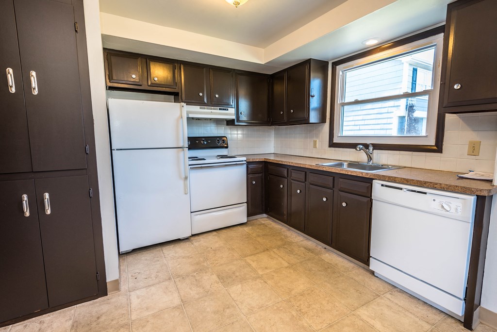 a kitchen with white appliances and black cabinets and a window