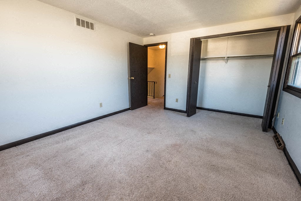 a room with a carpeted floor and a door to a closet