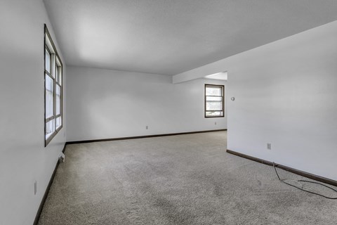 the living room of a house with carpet and white walls