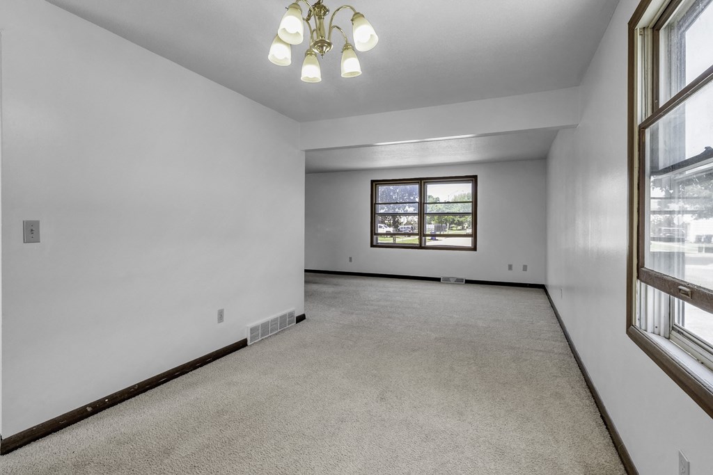 the living room of an empty house with white walls and a window