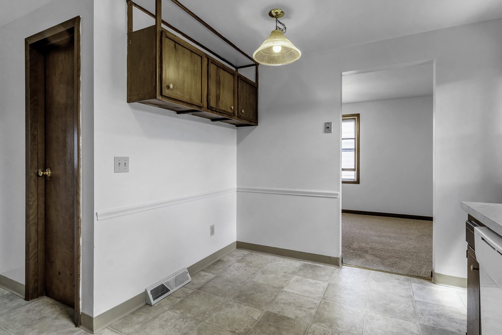 an empty kitchen with white walls and white tile flooring and a door to a