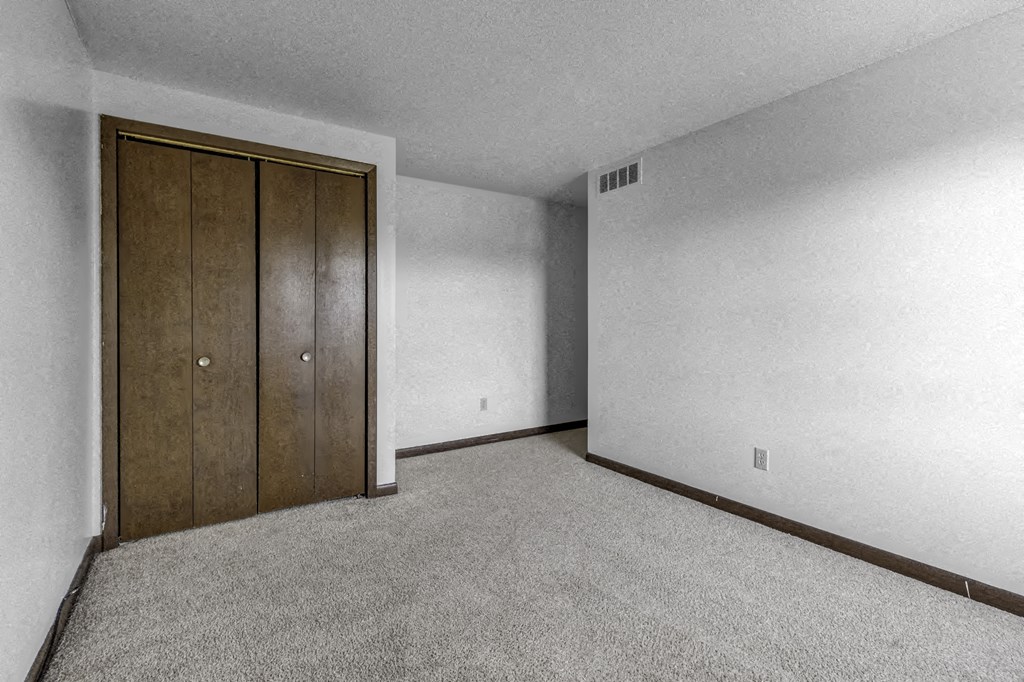 a bedroom with a closet and a carpeted floor