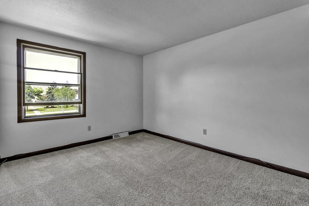 the living room of a house with white walls and a window
