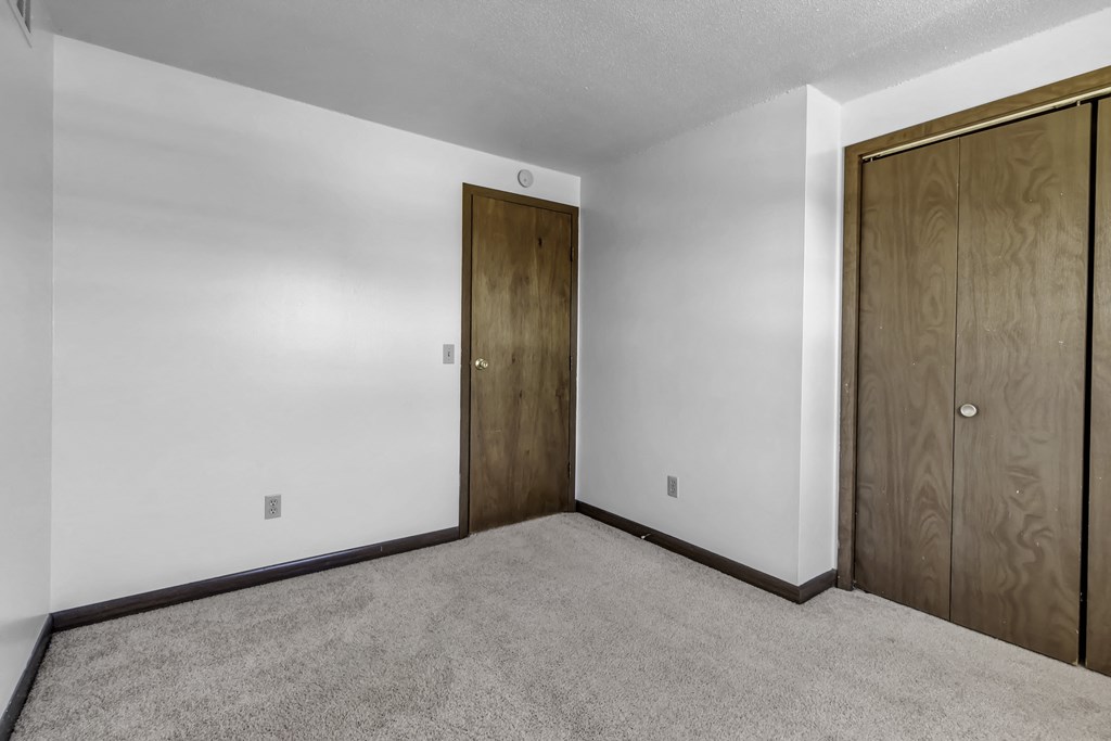 an empty room with carpet and a door to a closet