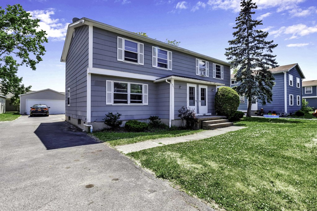 a blue house with a car parked in the driveway