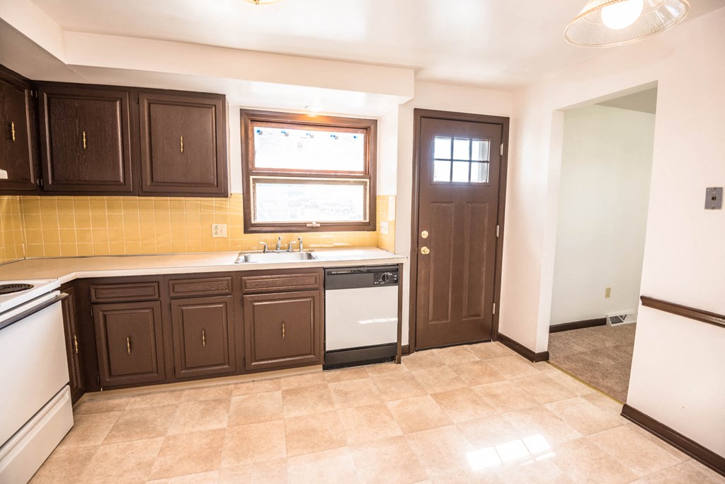 a kitchen with dark cabinets and a sink and a door
