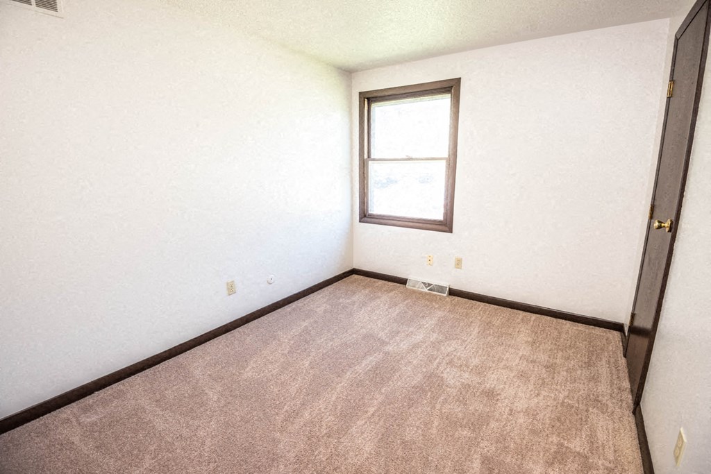 an empty room with a window and a carpet