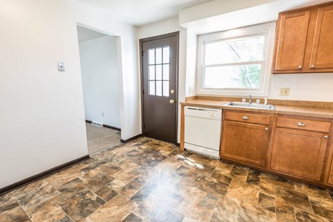a kitchen with wooden cabinets and a sink and a door